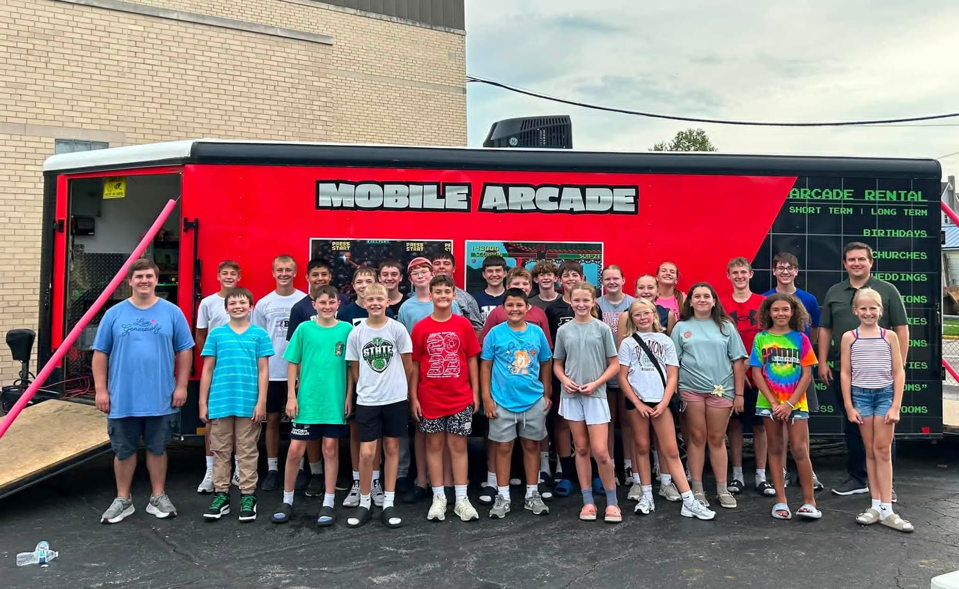 Zion Church Youth Group posing in front of The Arcade Rental's mobile arcade trailer in Decatur, Indiana